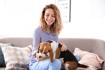 Young woman with her dog on sofa at home