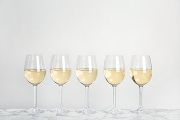 Glasses with white wine on light background