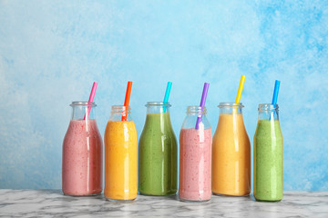 Fototapeta na wymiar Bottles with fresh tasty smoothies on table against color background