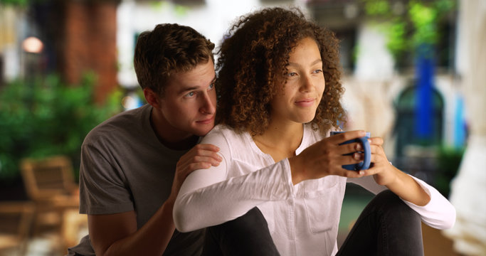 Pretty black woman sits outside drinking coffee with her boyfriend