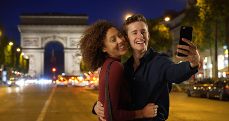 Happy and attractive couple take a selfie on Paris street at night