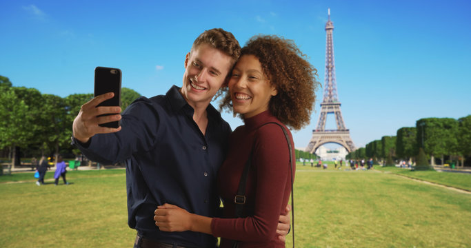 Caucasian male and African female take picture together on honeymoon in Paris