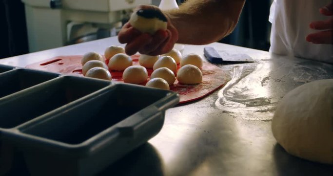 Male chef applying poppy seeds on rolled dough balls 4k