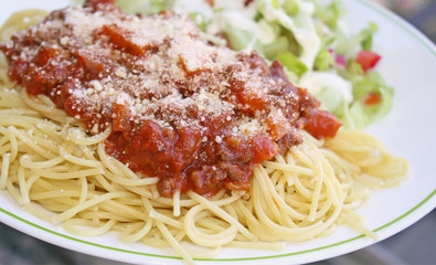 Cooked spaghetti pasta topped with a delicious homemade meat sauce and freshly grated Parmesan cheese and a fresh garden side salad topped with creamy Ranch dressing 
