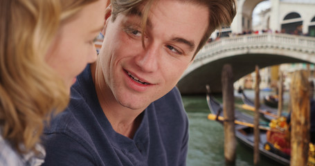 Obraz na płótnie Canvas Side view of happy millennial couple in Venice talking near Italian bridge