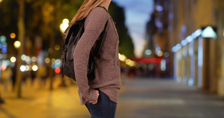Caucasian woman with her backpack standing on urban street at night