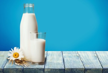 Glass of milk and bottle on background
