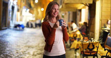 Casual portrait of woman drinking coffee outside restaurant at night