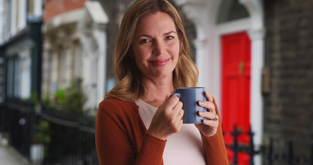 Close up portrait of woman drinking coffee outside residence
