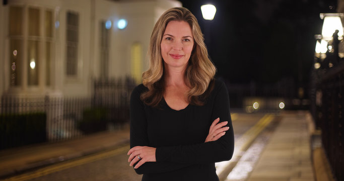 Smiling Caucasian woman posing for a portrait outside at night