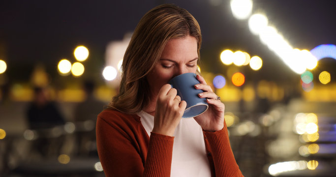 Close up portrait of woman drinking coffee outside at night