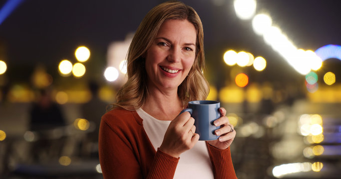 Close up portrait of woman drinking coffee outside at night