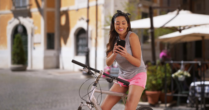 Cute smiling Latina woman on her bike using smartphone for directions © rocketclips
