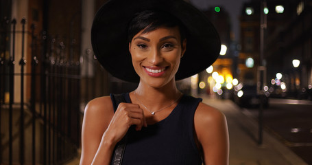 Young attractive black female in urban setting posing with her purse and hat