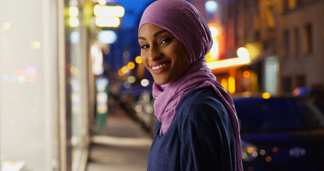 Beautiful young Muslim woman in urban setting smiling at camera