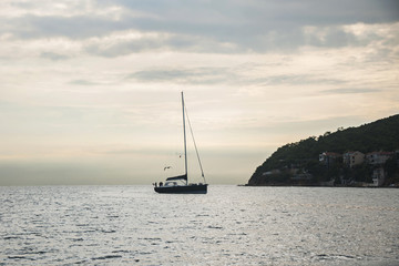 A yacht slowly sailing in the sea at sunset