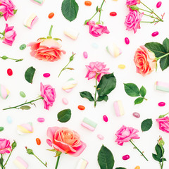Pink or orange roses flowers and marshmallow with colorful candy on white background. Flat lay, top view. Holidays background