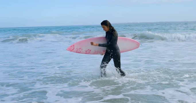 Female surfer with surfboard running towards the coast 4k