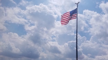 Flag flying in bly sky cliuds