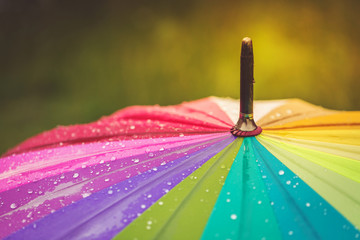 Surface of rainbow umbrella with raindrops on it. Close up, copy space.