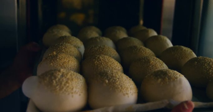 Chef inserting tray of unbaked rolled dough 4k