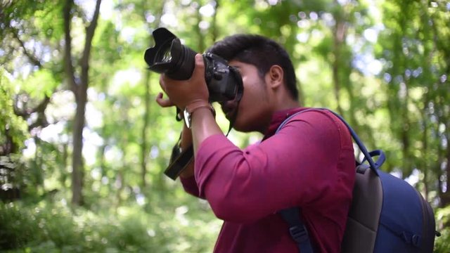 A photographer shooting photos of birds and trees in a forest with his DSLR camera in slow motion
