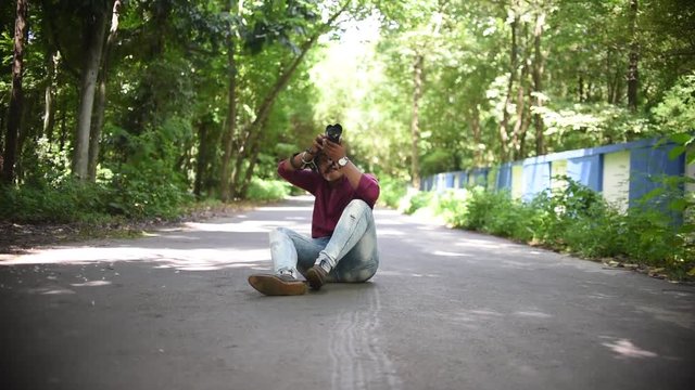 A photographer sitting on middle of a road and shooting photos of birds and trees and other objects