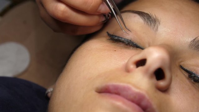 Removal of old lashes. The beautician removes the eyelashes with tweezers. Eyelash extension. Beautiful young woman on eyelash extension procedure.