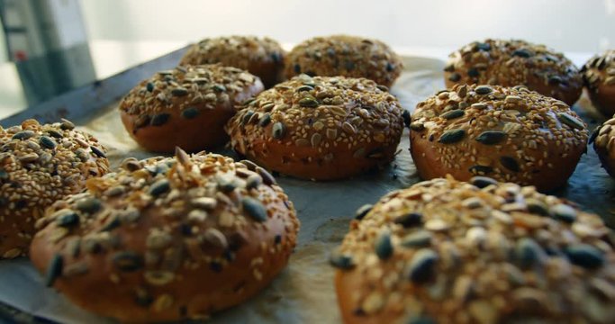 Baked buns topped with mixed seeds placed on tray 4k
