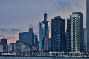 Fototapeta na wymiar Sunset reflecting off of skyscrapers, with view of sailboats in a Lake Michigan marina in foreground, along Lake Michigan's lakefront in downtown Chicago.