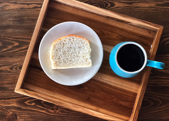 Breakfast with Black coffee cup and Homemade bread in with dish on the beautiful wooden table. Fulfill energy. 