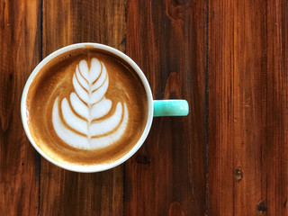 Heart latte art coffee in green and white cup on the vintage wooden table with natural light .Wake up and full fill energy, top view and copy space