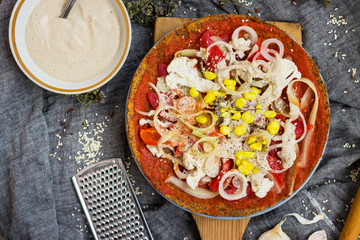 Raw vegan pizza with dehydrated dough, raw tomato sauce, vegan mayonnaise, corn and fresh vegetables. Healthy Italian food