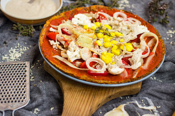 Raw vegan pizza with dehydrated dough, raw tomato sauce, vegan mayonnaise, corn and fresh vegetables. Healthy Italian food