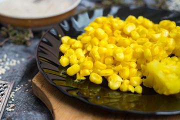 Cooked corn kernels grain on black glass plate. Vegan lunch, vegetarian dinner. Healthy dietary food