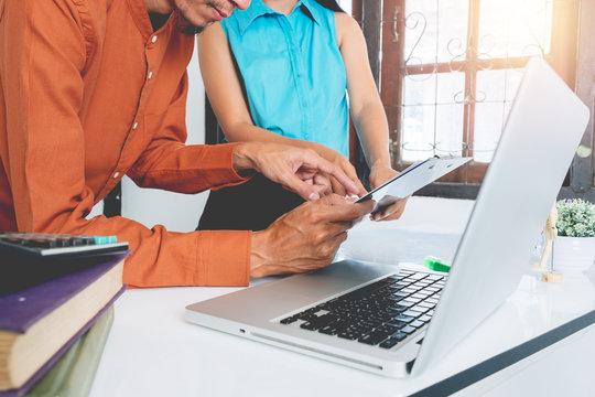 Mature business man and younger colleague using laptop and business document to discuss information on white desk table at office.Business people meeting concept. - Powered by Adobe