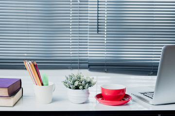 Workplace with notebook laptop and office supplies Comfortable work table in office windows .