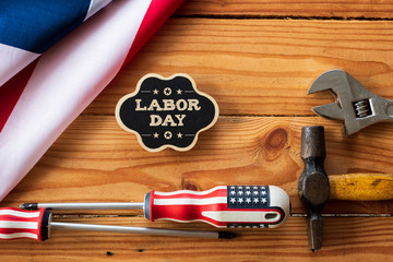 USA Labor day concept, First Monday in September. Different kinds on wrenches, handy tools, America flag and wooden tag on wooden table.