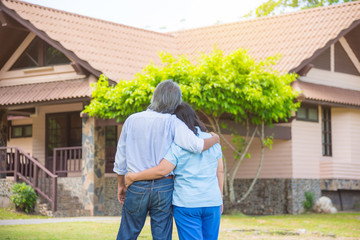 Asian senior couple from behind looking at front of house