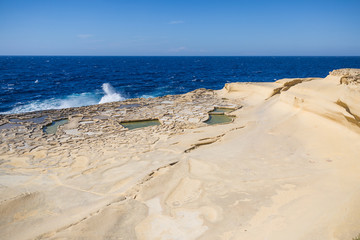 Fototapeta na wymiar Waves Crashing on Gozo Natural Salines with Mediterranean Sea in the Background
