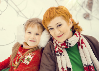 mom and daughter, both red hair walking in costumes of flowers traditional elves Santa's helpers in the winter forest under the snow with a chest of gifts and giant candy