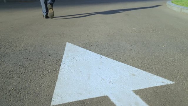 Man walking along white arrow, person choosing own life path, going right way