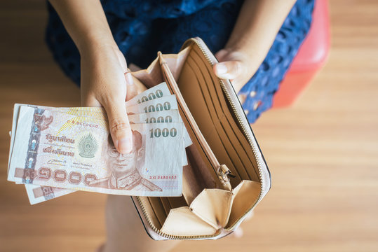 Hands woman counting Thai baht banknote bills into wallet