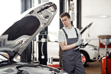 At the end of the working day: a young automechanic is looking a