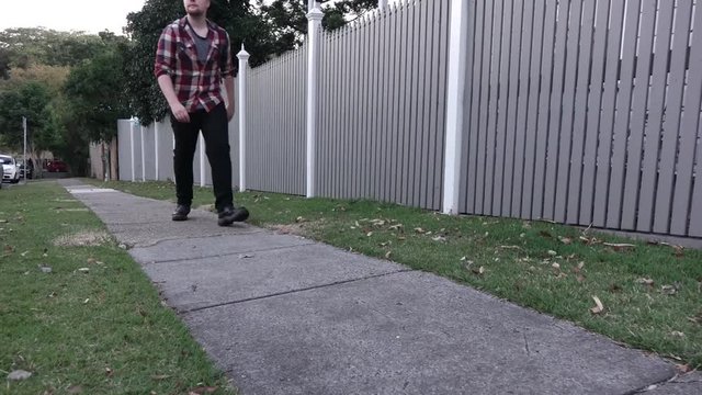 Young casual millenium guy walking on a footpath