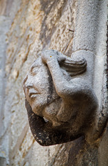 Fototapeta na wymiar Medieval Sculpture of a head, supporting column in portal of Saint-Nicolas church, Neufchâteau, France