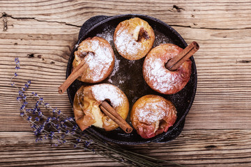 Baked apples with cinnamon sticks in cast iron skillet