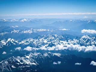 Obraz premium Aerial view from the airplane, clouds and snow over the mountains