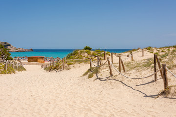 View of the Mediterranean Sea and sandy paths through the protected dunes to Cala Agulla beach on...