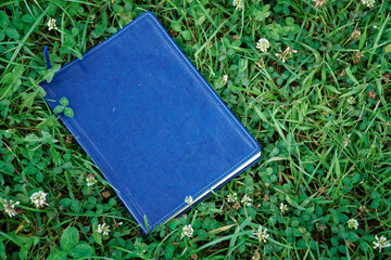 Blue notebook on the green grass in park